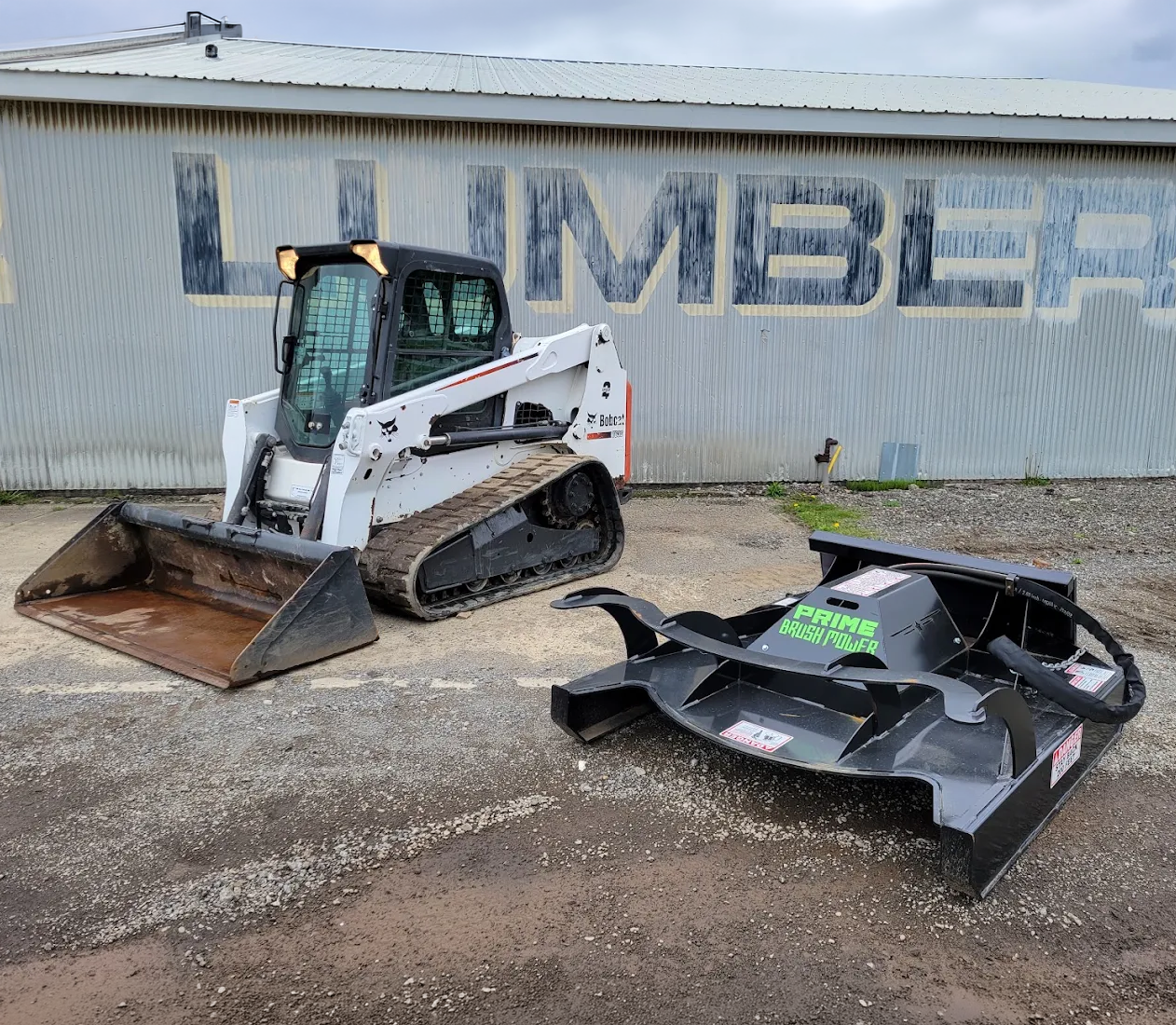 White Bobcat compact track loader with bucket and brush cutter attachment at Keystone Equipment