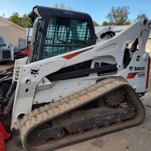 Bobcat T870 compact track loader viewed from the side, with cab guard, rubber track and red front attachment